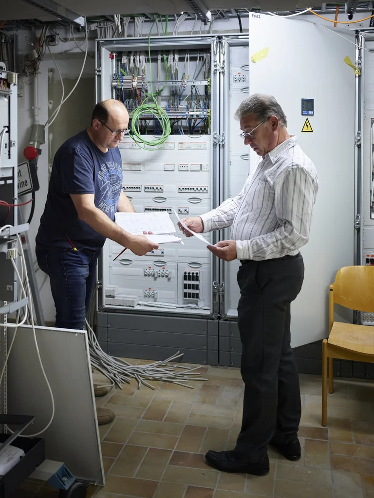 Haustechniker stehen vor dem Elektrokasten