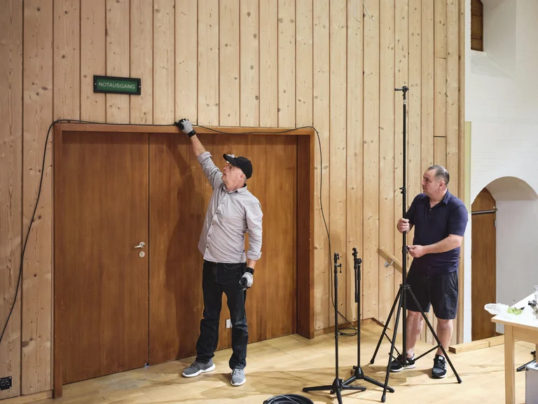 Zwei Tontechniker verlegen Kabel auf der Bühne
